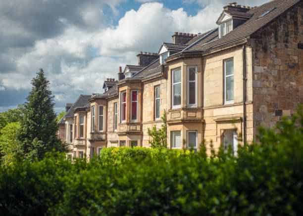 blonde sandstone terraced homes on a tree lined street in glasgow scotland